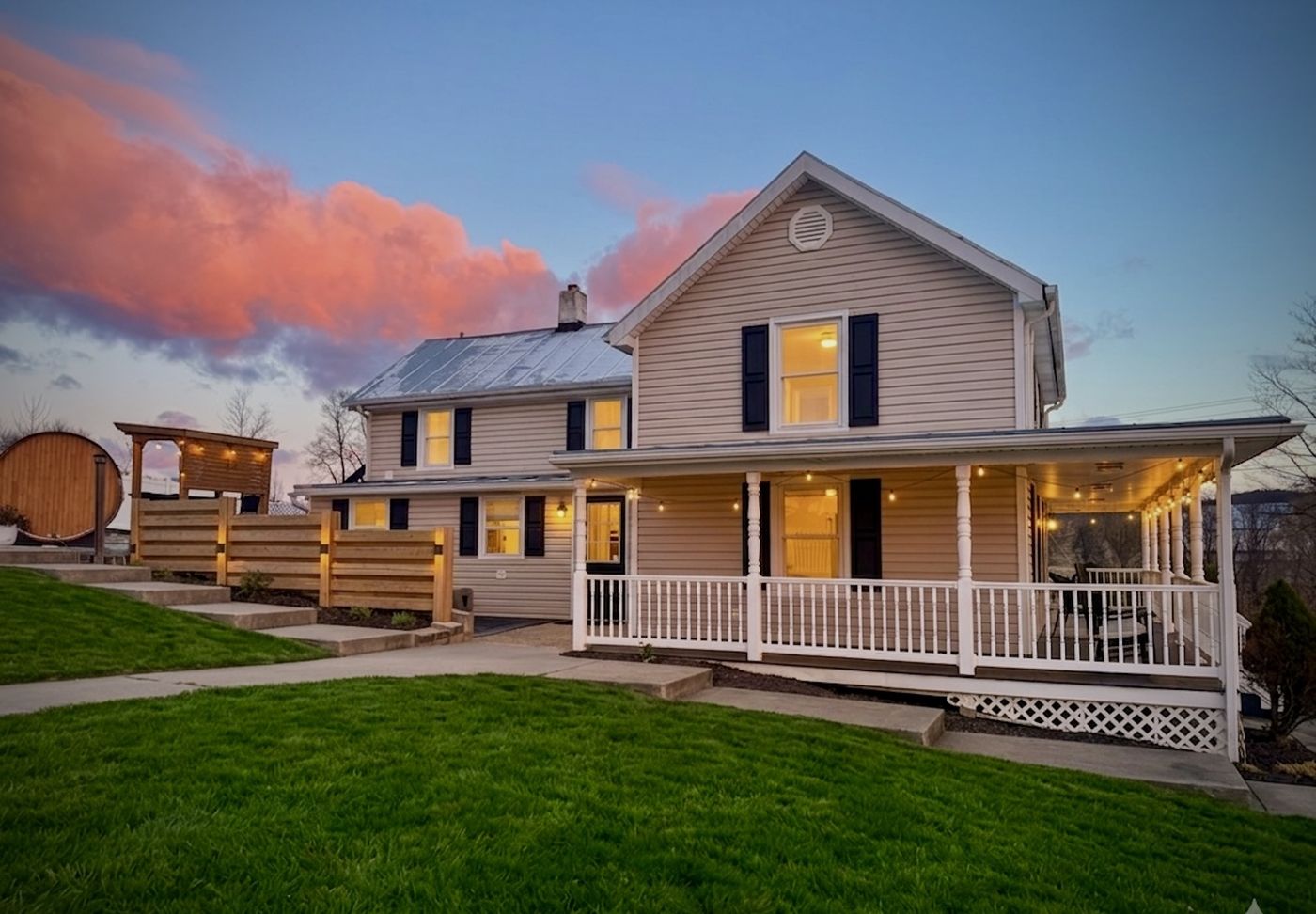 Blue Ridge Farmhouse Retreat at sunset with the wraparound porch lit up